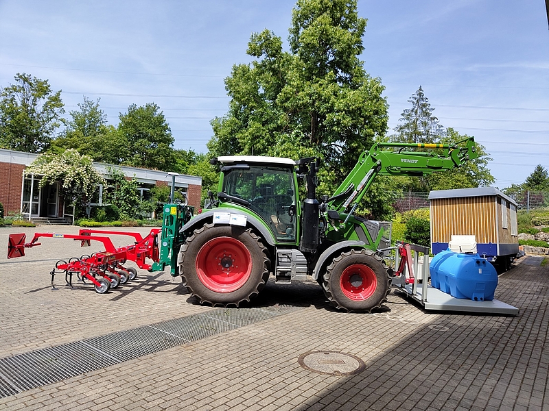 seitliche Ansicht des Traktors mit Hackmaschine, Verschieberahmen und Wassertank vorne 