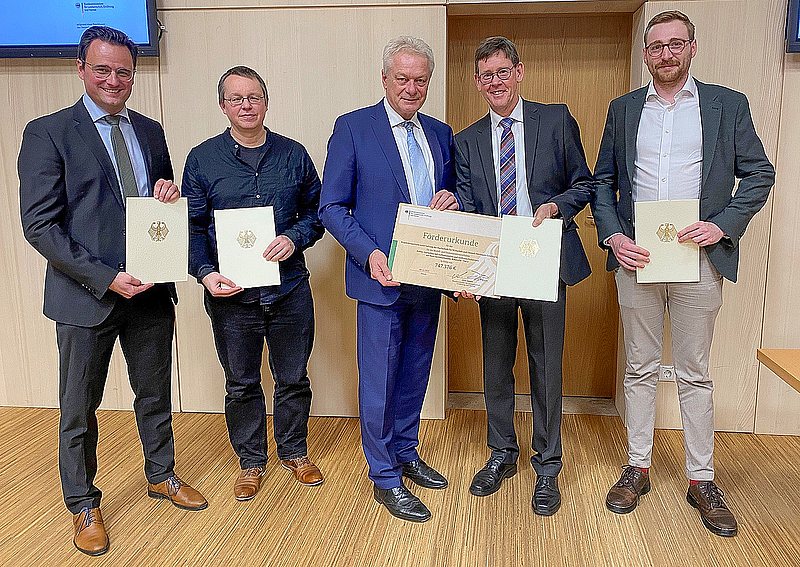 5 Personen stehen in der Reihe und halten die FörderurkundeFöderbescheid