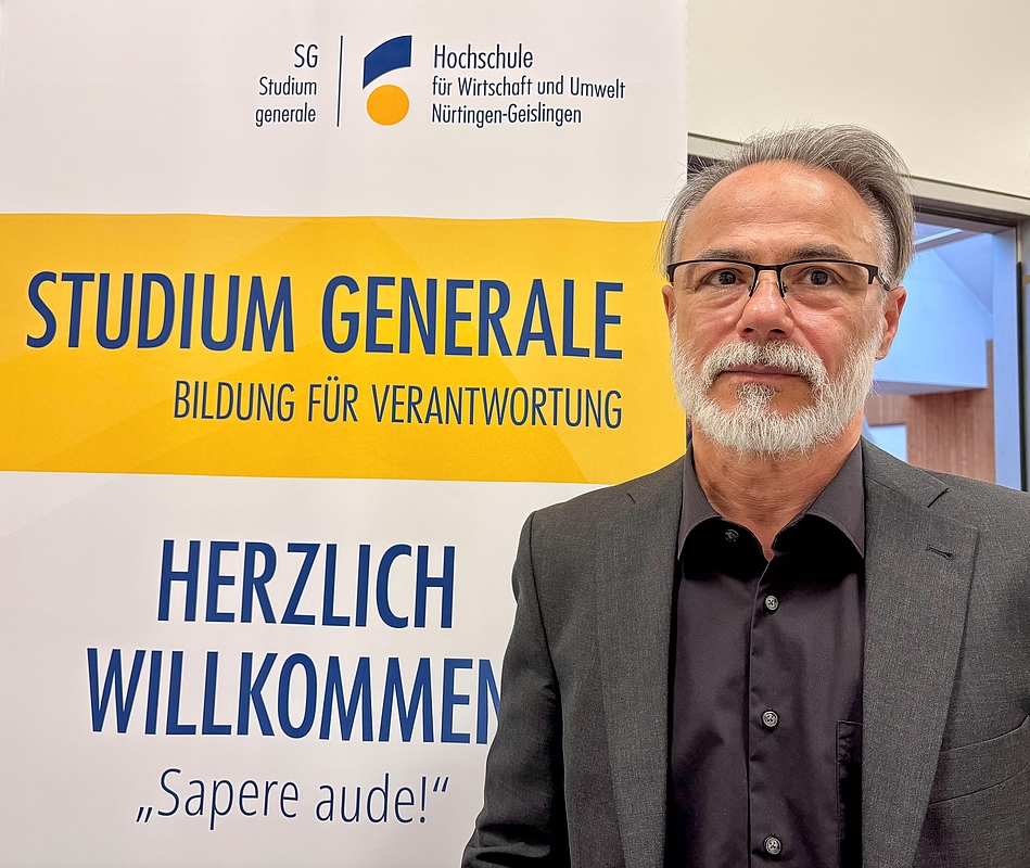 Referent vor einem Werbeaufsteller "Studium generale"