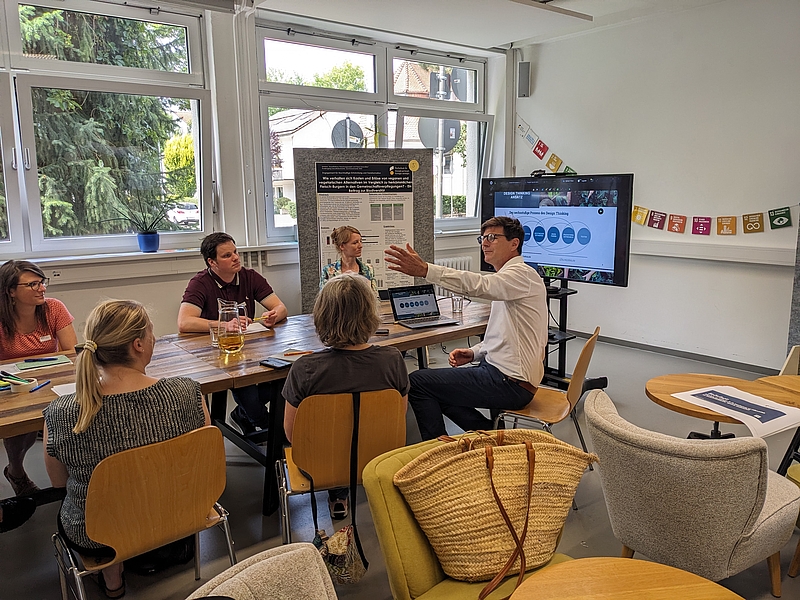 Teilnehmende des Workshop sitzend am Tisch vor de,m Präsentationsbildschirm