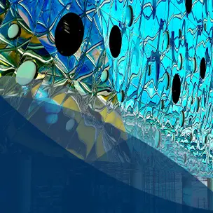 Innenraum eines modernen Gebäudes mit geometrischem Glasdach, reflektierenden Deckenpaneelen und hohen Säulen, erfüllt von natürlichem Licht und Besuchern.