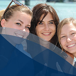 Gesundheits- und Tourismusmanagement B.A. studieren Drei Studierende lachen in die Kamera vor einem See