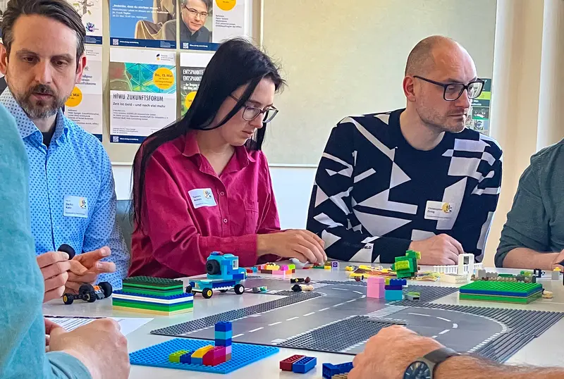 Personen am Tisch mit Legosteinen