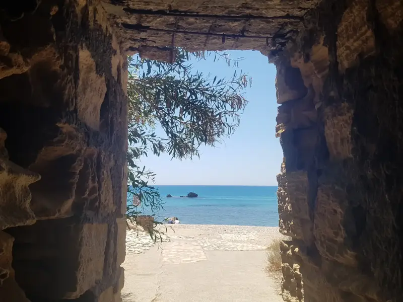 Steintor mit Blick auf Strand, Meer und Zweig im Sonnenlicht
