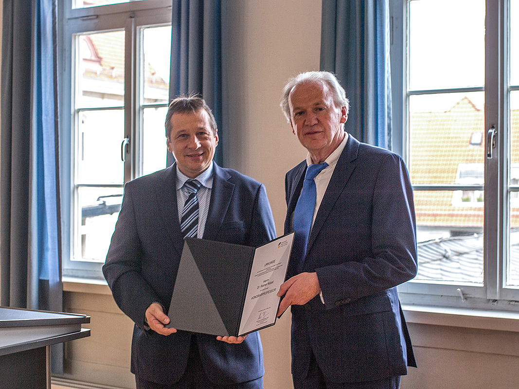 HfWU-Rektor Prof. Dr. Andreas Frey, links, übergibt die Ernennungsurkunde zum Honorarprofessor an Dr. Rainer Nübel, rechts.