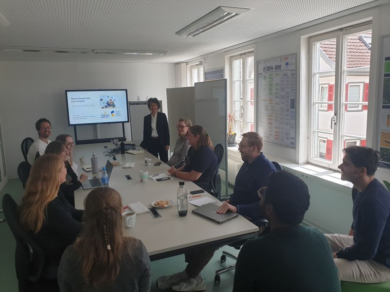 Workshopteilnehmer um den Tisch sitzend mit der Dozentin 